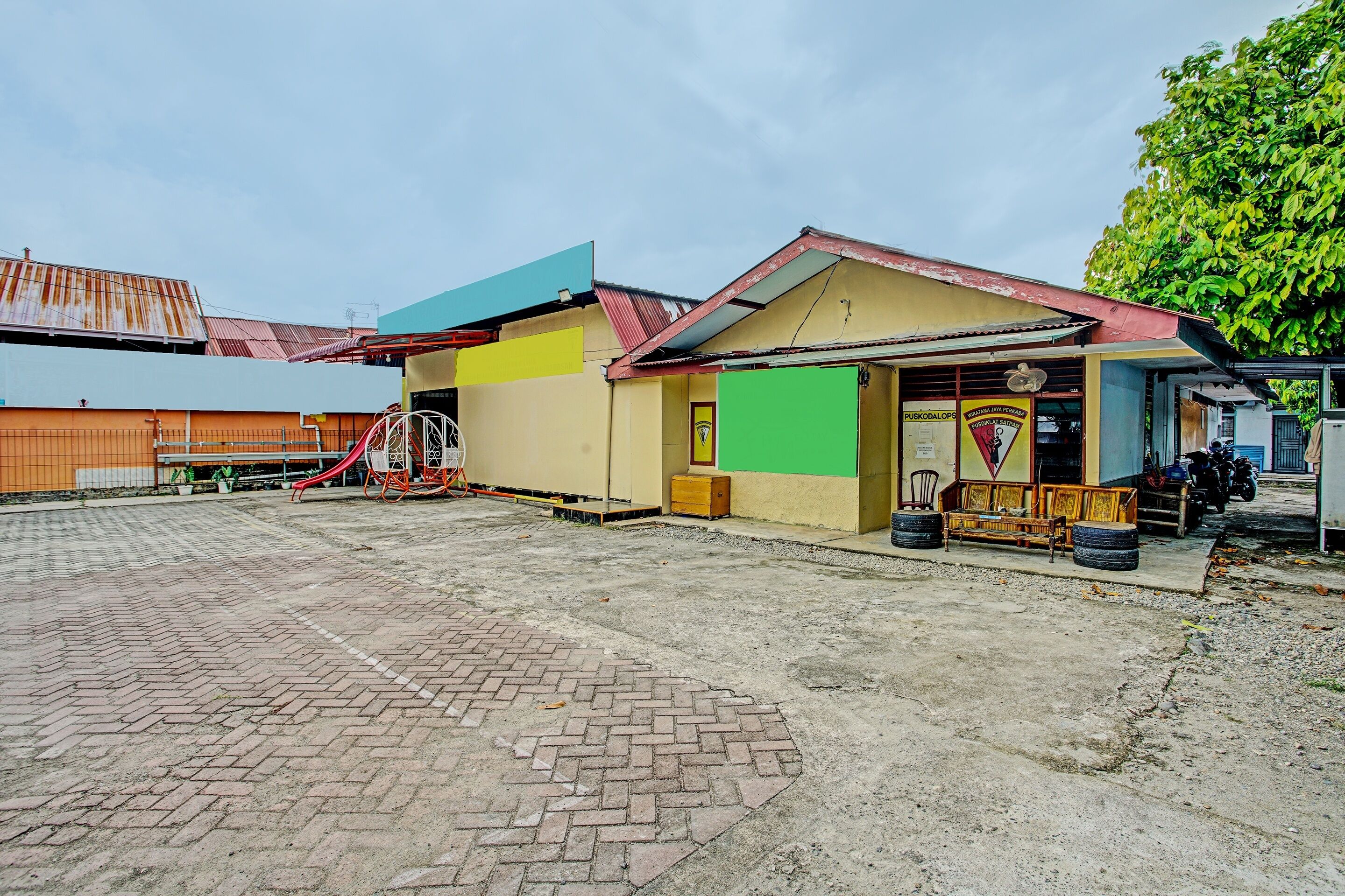 A building with a green door, a signboard, and a small seating area with tires.