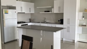 Una cocina moderna con armarios blancos, una isla central y un comedor con mesa y sillas.