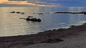 Un paisaje costero con costa rocosa y mar tranquilo.