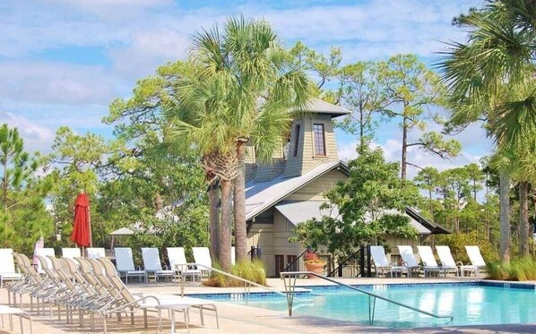 A pool area with lounge chairs and a building with a sloped roof.
