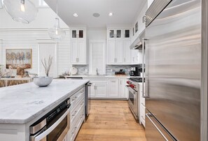 A modern kitchen with white cabinetry, stainless steel appliances, and a marble countertop. - Watercolor Resort |Private Pool | 6 Pass Golf Cart (Santa Rosa Beach)