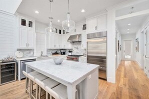 A modern kitchen with white cabinetry, stainless steel appliances, and a central island with bar stools.