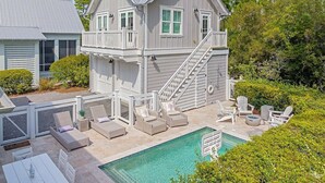 Ein zweistöckiges Haus mit Pool, Sitzgelegenheit im Freien und einer Treppe, die zum oberen Stockwerk führt.