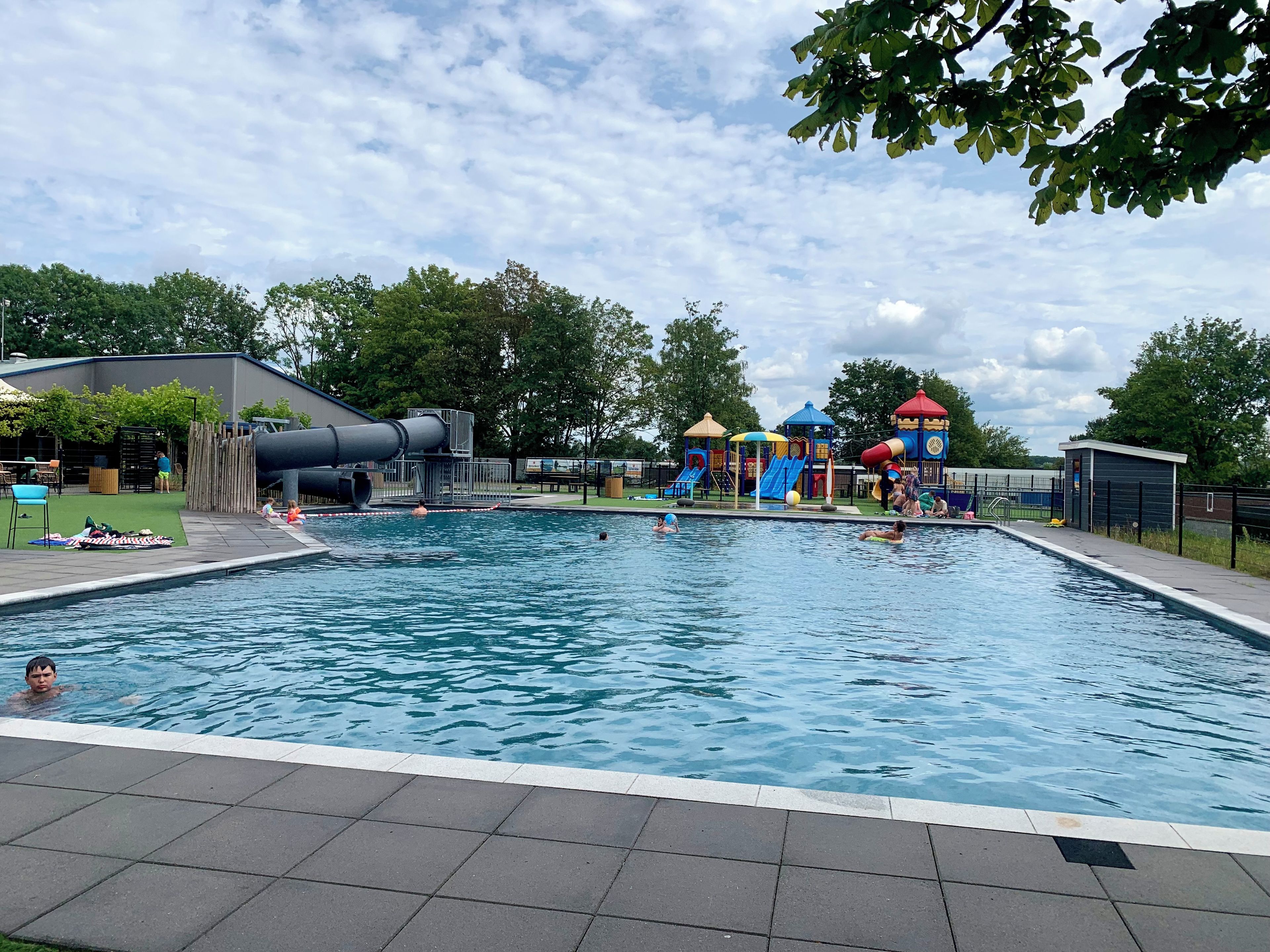 A swimming pool with a slide and play structures.