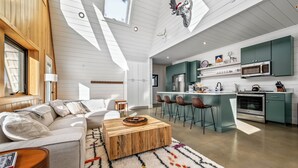 Una cocina moderna con una isla central, taburetes de bar y un microondas.