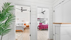 Una habitación con cama, mesita de noche, ventilador de techo y ventana.