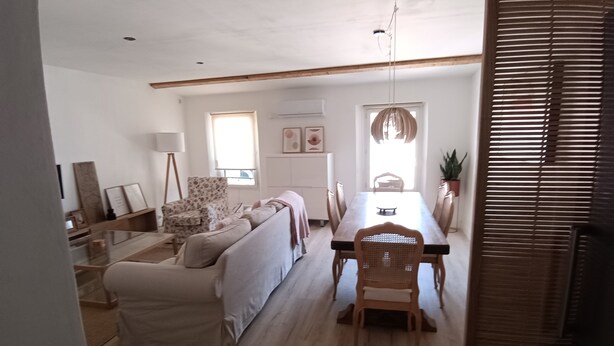 A modern living room with a sofa, dining table, and chairs. There is a lamp, a chair, and a potted plant. - Cosy, spacious air-conditioned apartment with all mod cons (Puget-ville)