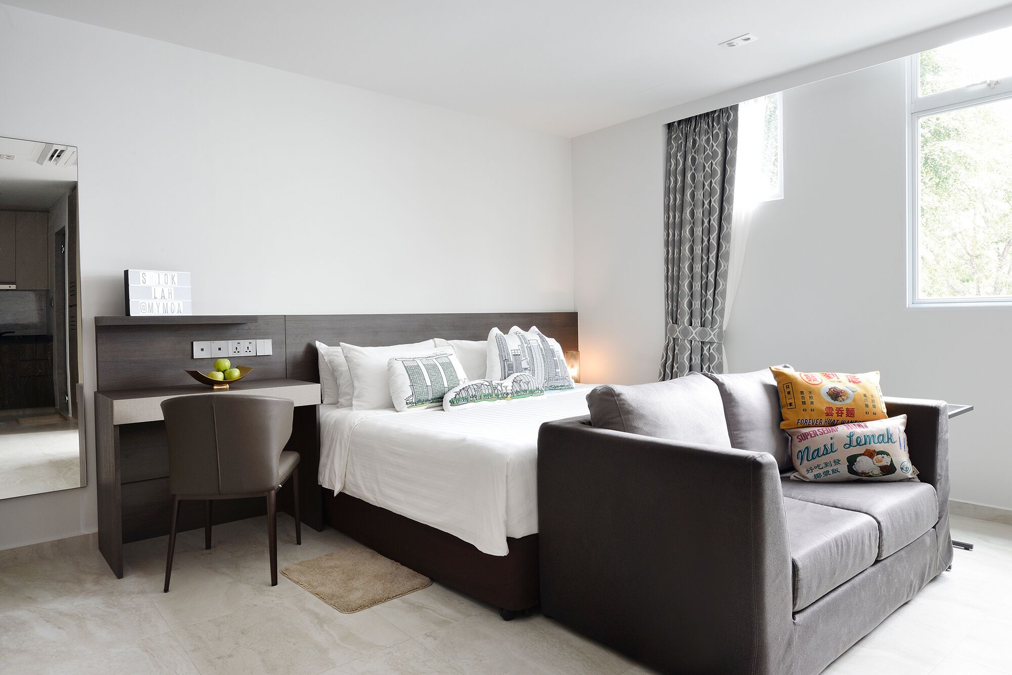A modern bedroom with a bed, a desk, and a sofa.