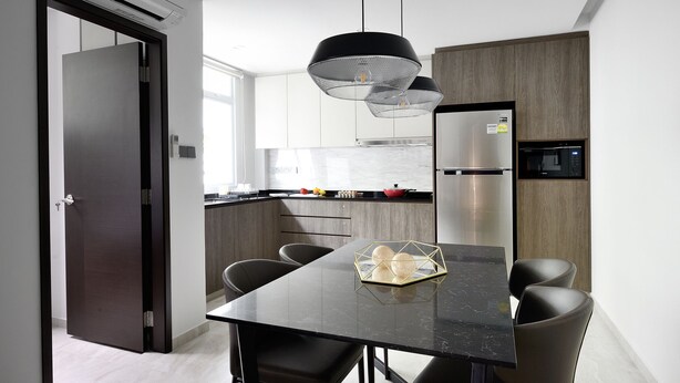 Una cocina moderna con una mesa de comedor negra, sillas grises y un refrigerador de acero inoxidable.