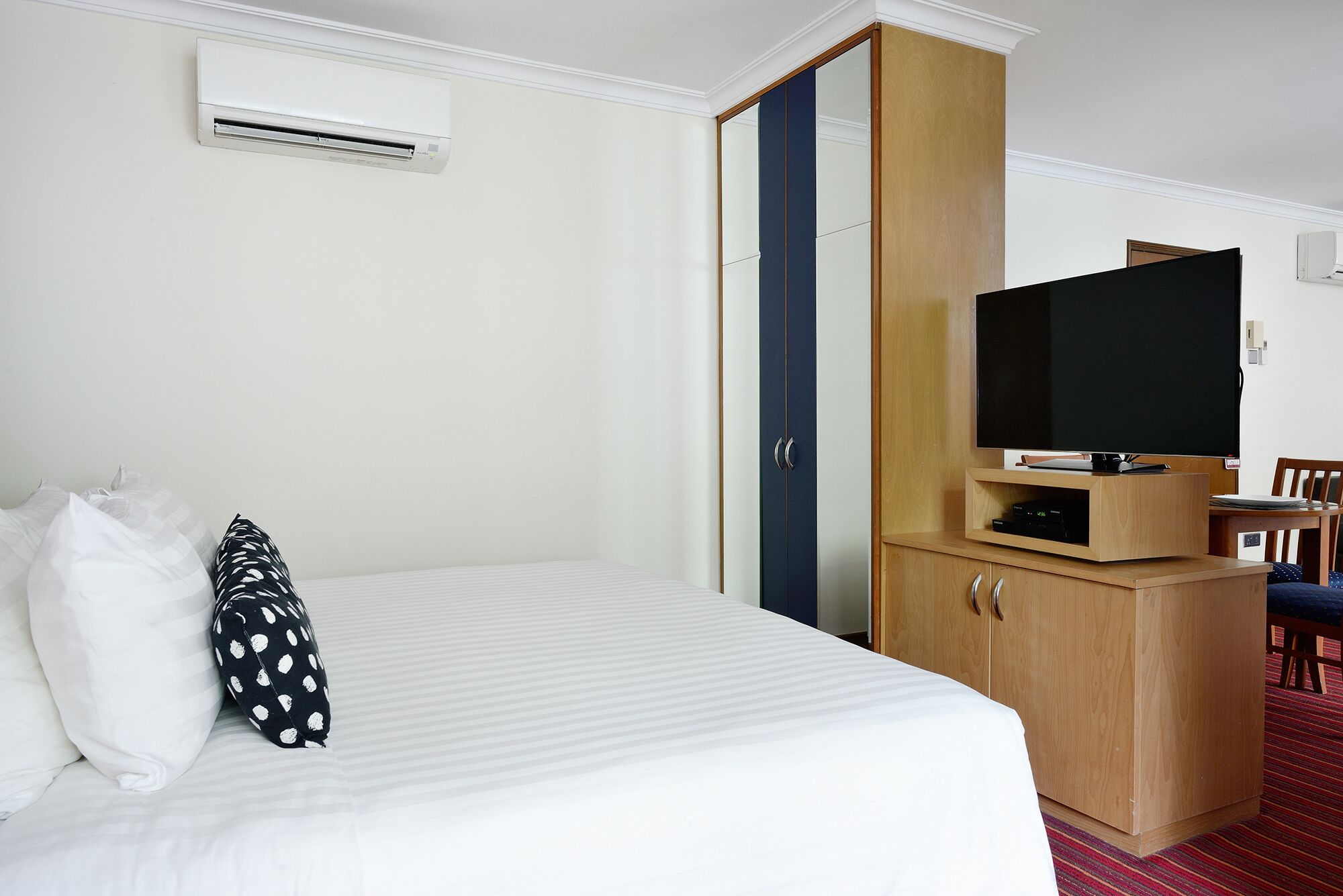 A hotel room with a bed, a wardrobe, a television, and a small table.
