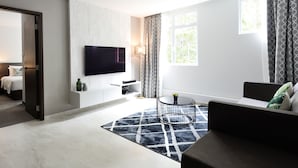 Una sala de estar moderna con un televisor de pantalla plana montado en la pared, un sofá, una mesa de centro y una alfombra estampada.