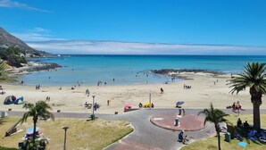 Een strand met mensen, tenten en een rond, verhard gebied met banken.