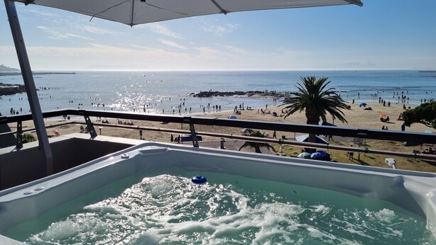 Een balkon met een jacuzzi met uitzicht op een strand.