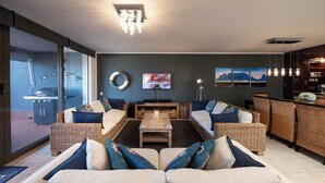 Een moderne woonkamer met rieten meubels, een televisie en kunstwerken aan de muur.