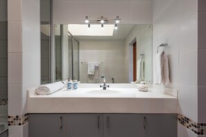 A bathroom with a large mirror, a white sink, and a towel rack. - Beach2Anchor (Cape Town)
