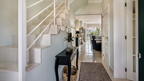 Ein modernes Interieur mit einer Treppe, einem Konsolentisch mit einer Vase und Blick in einen Essbereich.