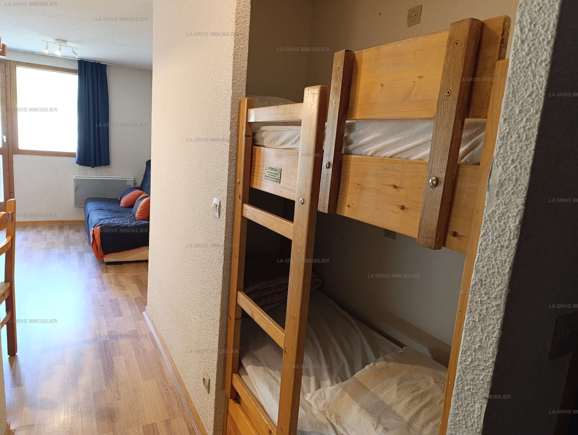 A room with a bunk bed, a sofa, and a window with curtains.