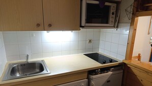 Ett kompakt kök med inbyggd mikrovågsugn, diskmaskin och diskho.
