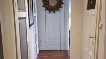 A hallway with wooden flooring, white doors, and a sunburst mirror on the wall.