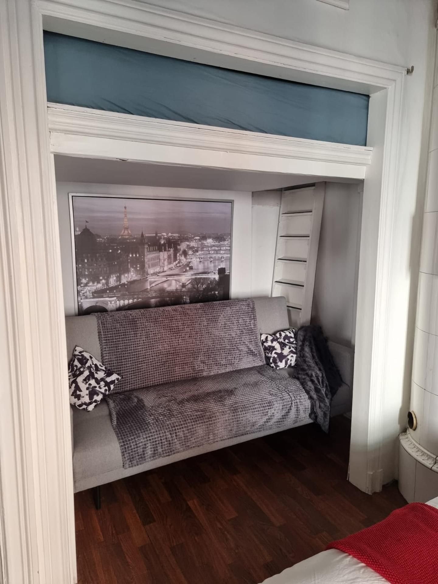 A room with a bunk bed, a cityscape poster, and a red blanket on the floor.