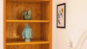 Ein hölzernes Regal mit einer Buddha-Statue, einem gerahmten Bild und einer kleinen Pflanze.