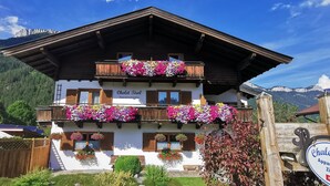 Un bâtiment de style chalet, doté de balcons en bois, de jardinières et d’une enseigne indiquant qu’il s’agit d’un chalet comprenant des appartements.