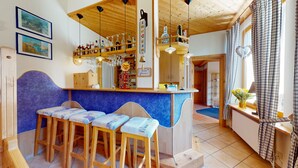 Un coin bar accueillant avec des tabourets en bois, un comptoir où sont exposées différentes bouteilles et un miroir au-dessus.