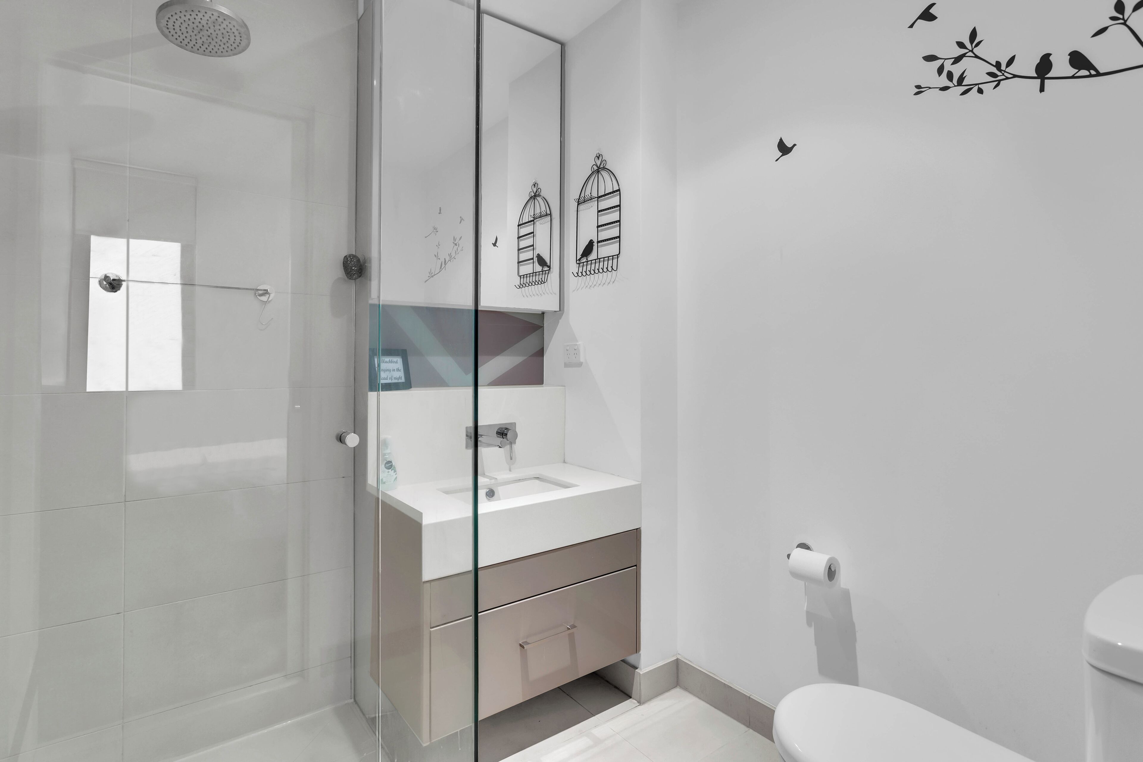 Ein modernes Badezimmer mit einer Duschkabine aus Glas, einem weißen Waschbecken und einer Toilette.