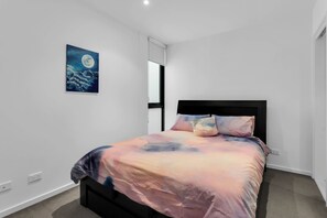 Cozy retreat with a neatly made bed, a black headboard, and a single pillow, complemented by a beautiful painting above.