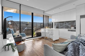 Enjoy the urban view from this spacious living area with a kitchen, comfortable seating, and a potted plant.