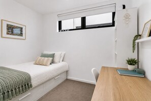 A bedroom with a bed, a desk, a window, and a wall-mounted shelf with plants. - Essendon North Sanctuary by Ready Set Stay (Essendon North)