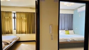 Twee aangrenzende hotelkamers met bedden, gordijnen en een telefoon.