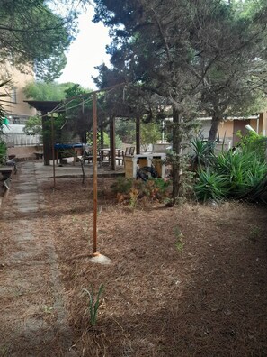 An outdoor patio area with a pergola, seating, and a small garden. - Three-room apartment a short walk from the ocean (Sardegna)