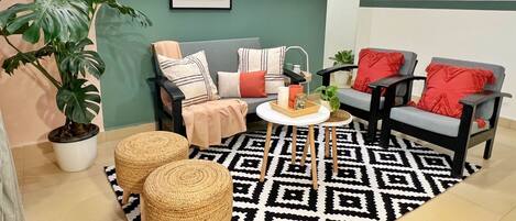 A cozy living room with a sofa, two armchairs, a coffee table, and a patterned rug.