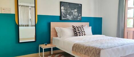 A bedroom with a bed, a nightstand, a mirror, and two wall art pieces.