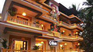 A multi-story hotel with balconies, a sign reading "Olive," and a tropical garden setting. - Olive Hotel Calangute Niwasa by Embassy Group (Calangute)