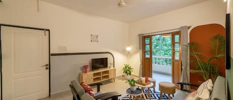 A living room with a sofa, a coffee table, a TV, and a potted plant.