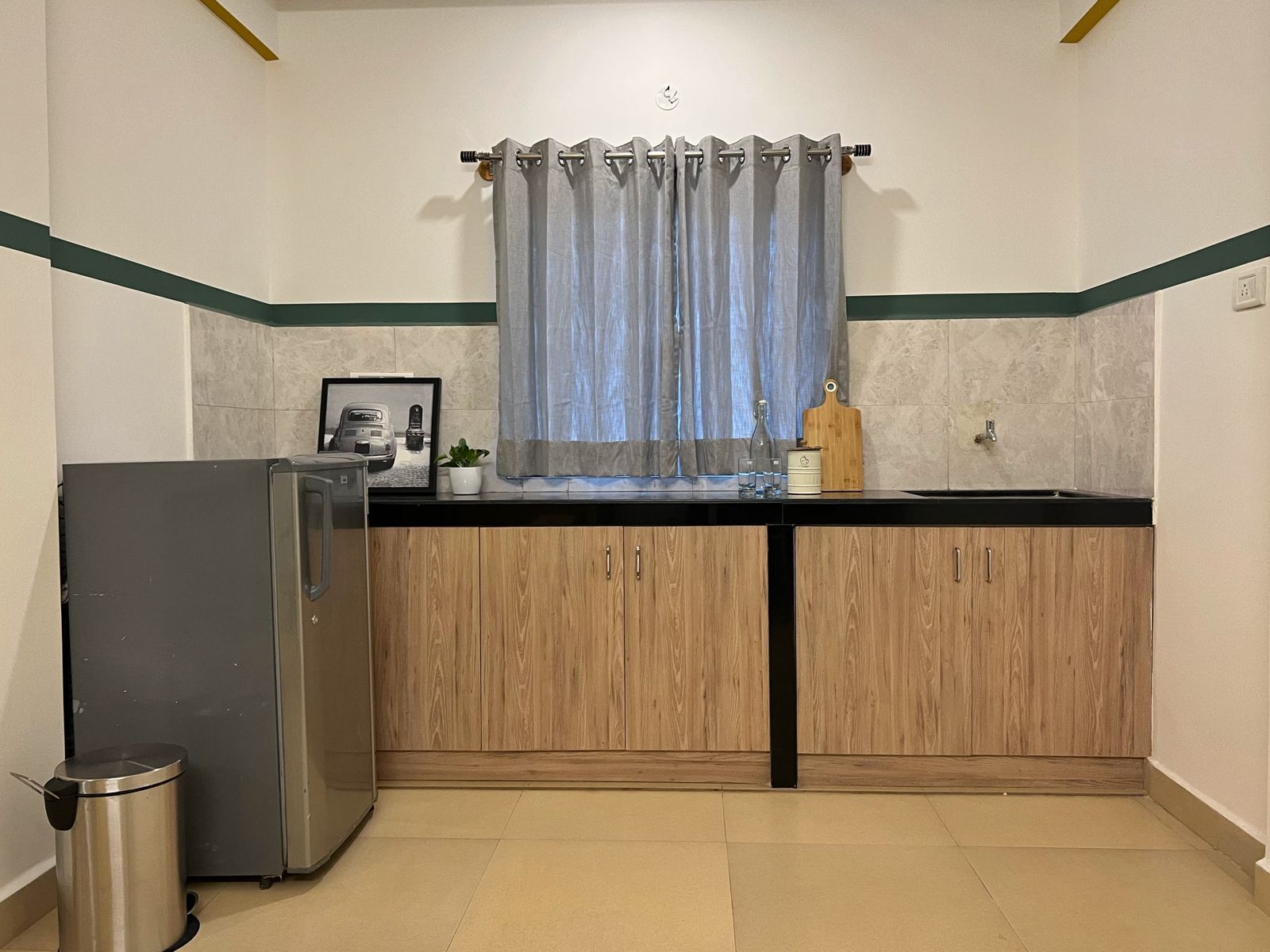 A compact kitchen with a refrigerator, a sink, and wooden cabinets.
