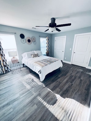 A bedroom with a bed, a ceiling fan, a window with blinds, and a door. - Boho Bliss Bungalow: Atlanta Retreat—Pet-Friendly (Atlanta)