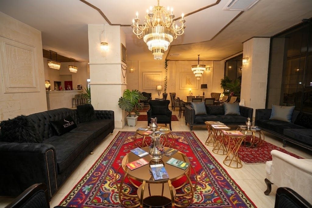 Ampla sala de estar com lustre, sofás, mesa de centro e tapete estampado.
