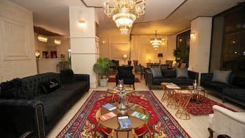 Ampla sala de estar com lustre, sofás, mesa de centro e tapete estampado.