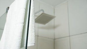 A bathroom with a white shower, tiled walls, and a towel hanging on a rack.