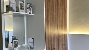 Una habitación con un armario blanco, un espejo y una estantería con libros y una lámpara.