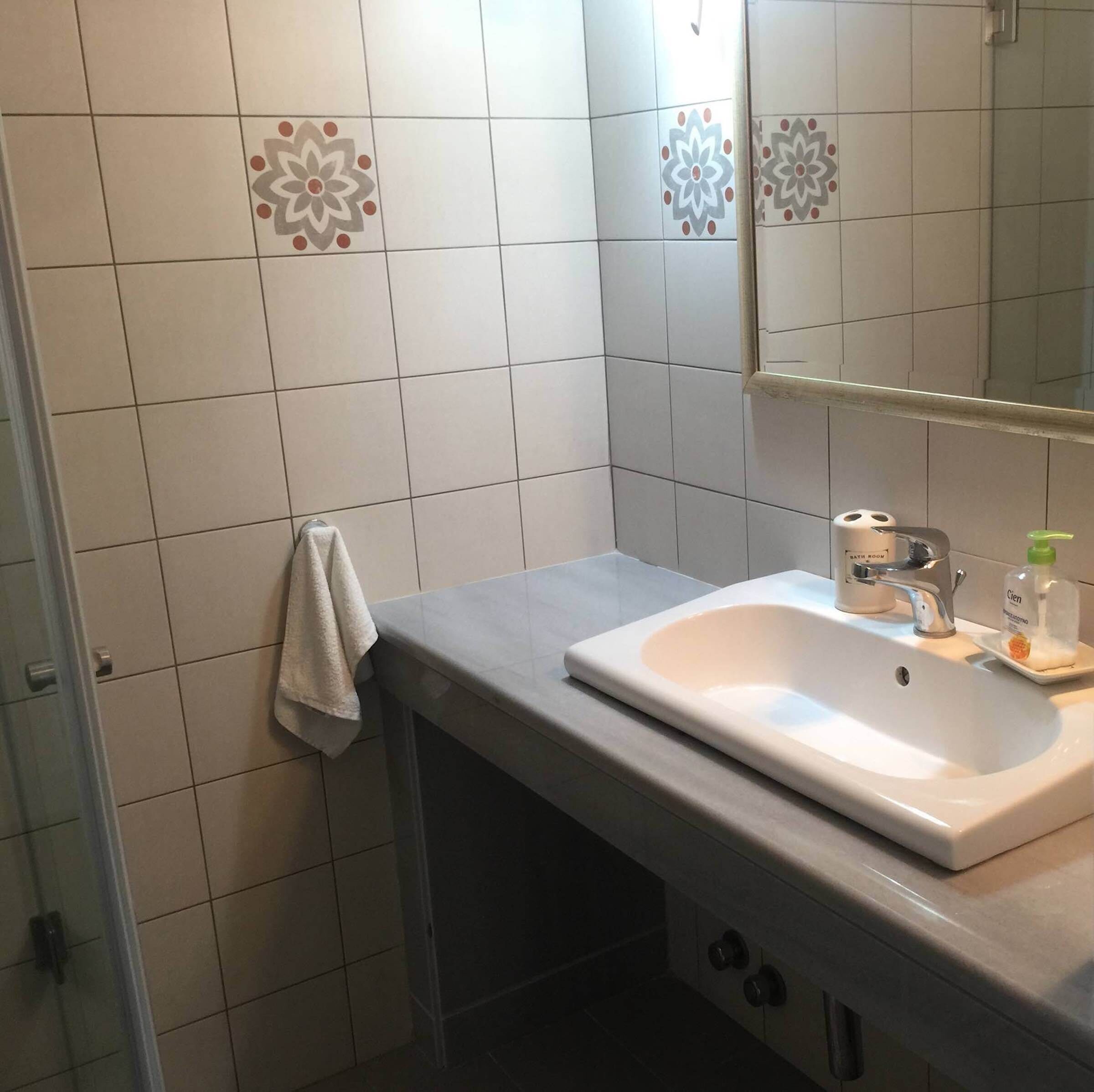 Ein Badezimmer mit einem weißen Waschbecken, einem Spiegel und einem Handtuch an der Wand.