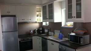 Eine kompakte Küche mit Kühlschrank, Backofen, Mikrowelle und Waschmaschine.