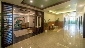 A hotel lobby with a reception desk, a seating area, and a hallway leading to other rooms.