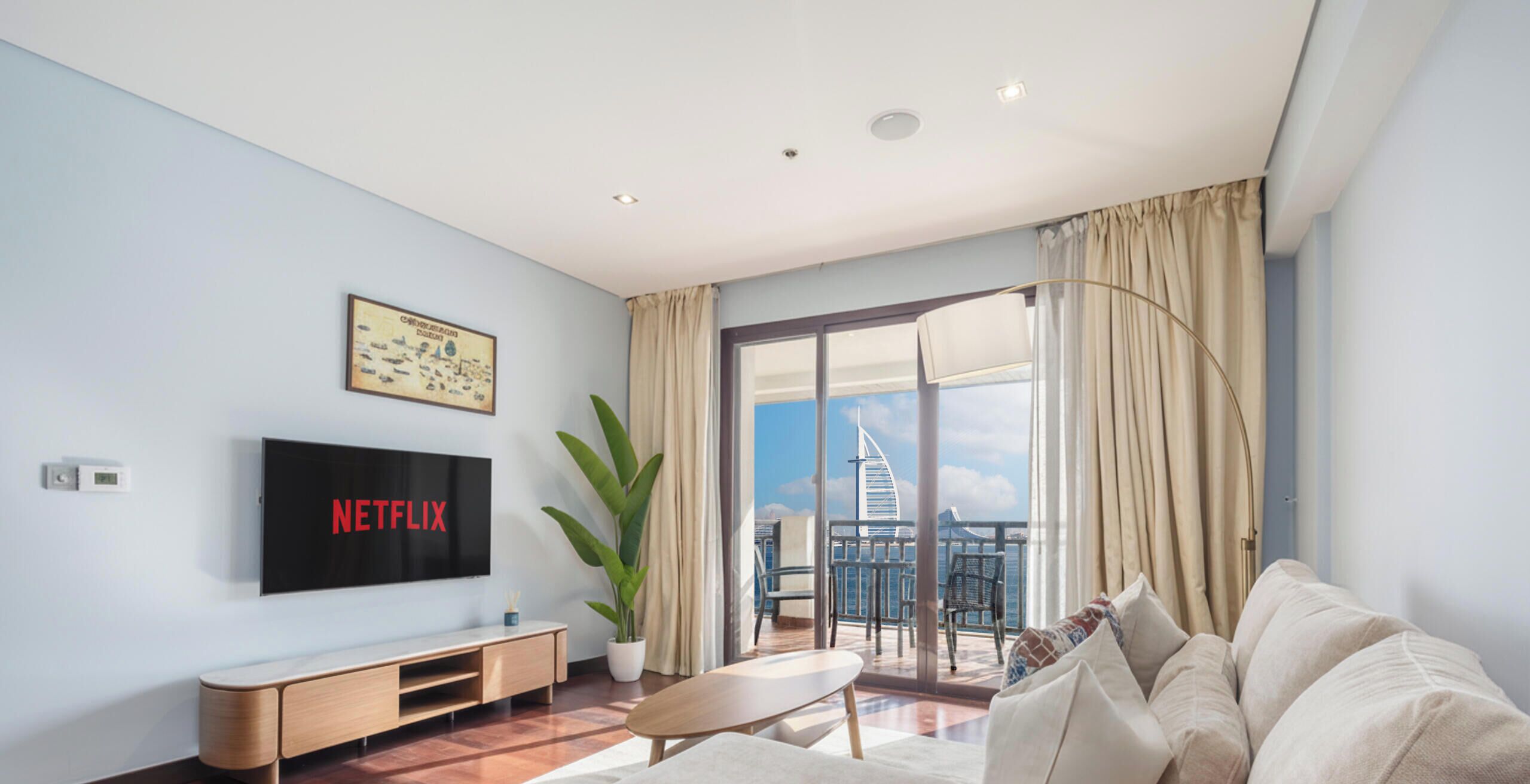 A modern living room with a flat-screen TV, a potted plant, and a balcony with a view of a landmark building.