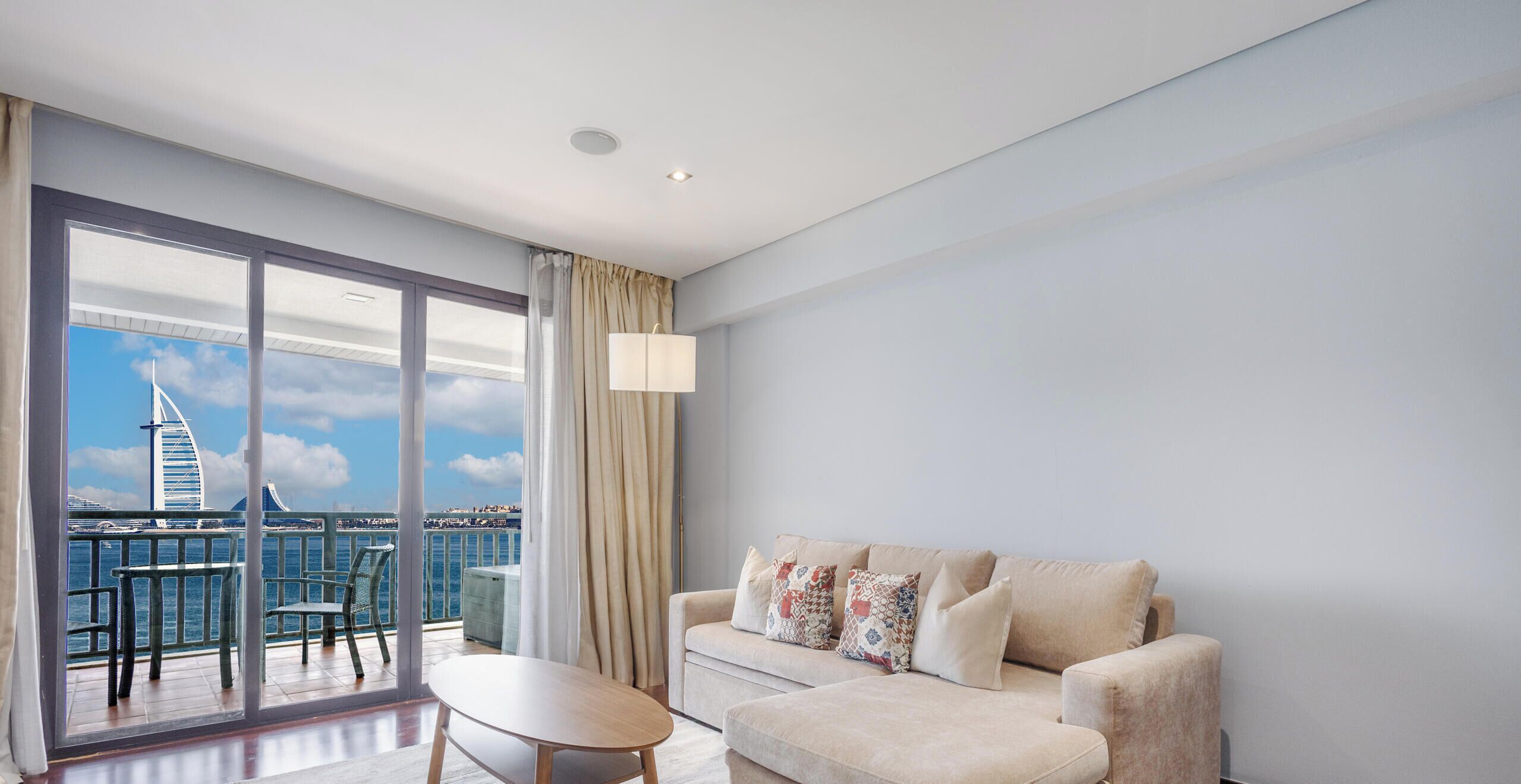 A modern hotel room with a balcony, a sofa, and a table.