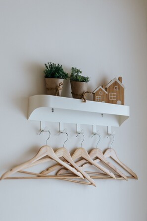 A white wall-mounted shelf with wooden hangers and two potted plants. - Fieldhome (Wujie)