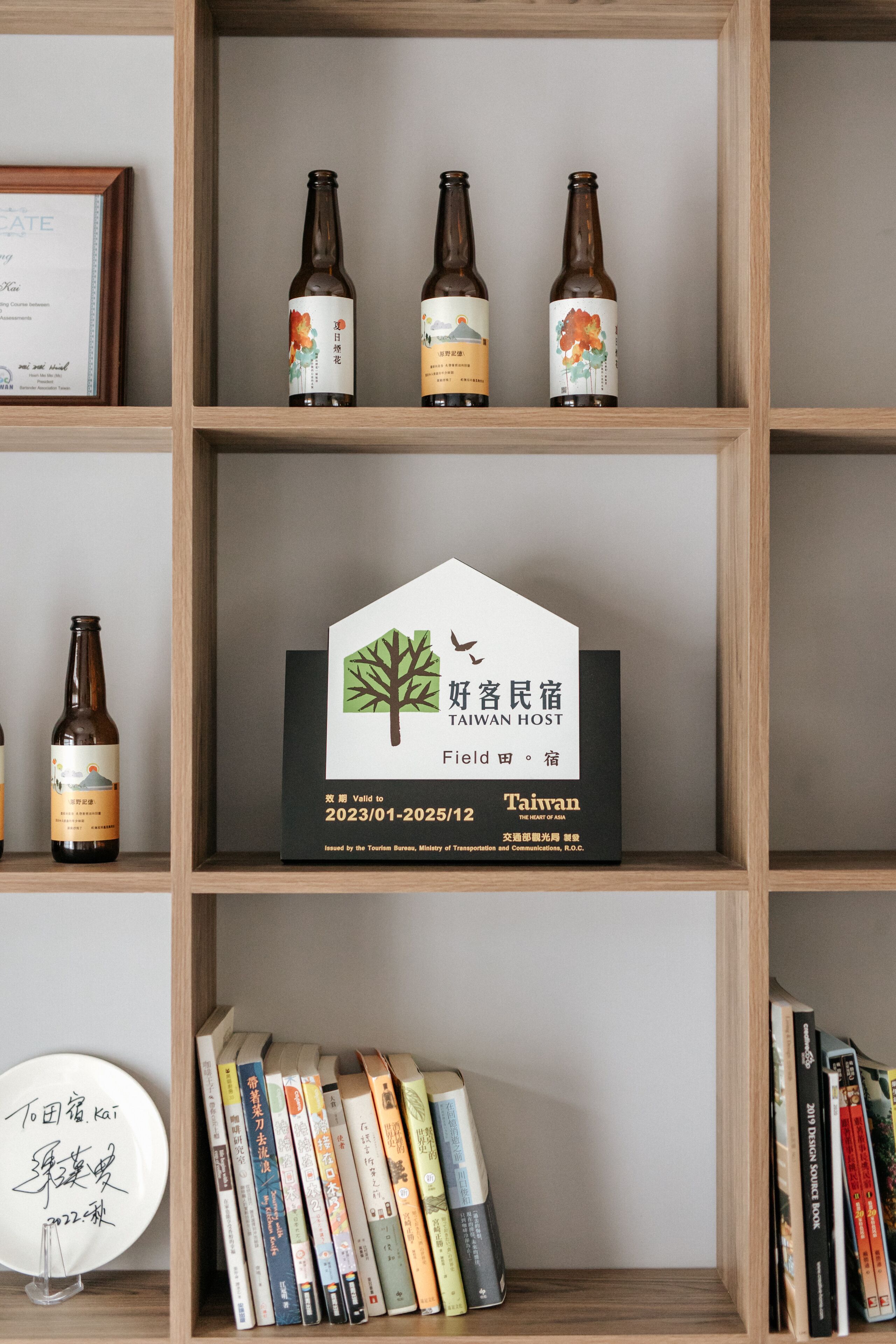Una estantería con libros y tres botellas de cerveza.